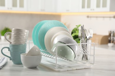 Many different clean dishware, cups and cutlery on white marble table in kitchen