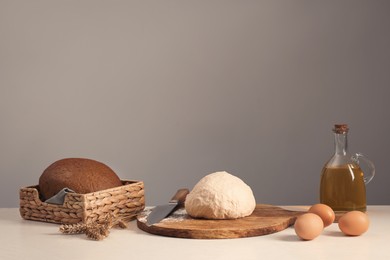 Photo of Fresh dough sprinkled with flour and other ingredients on white table near grey wall