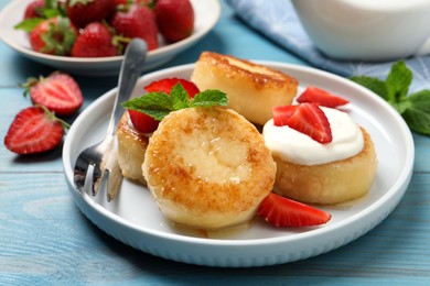 Photo of Delicious cottage cheese pancakes with strawberries, honey and sour cream on light blue wooden table, closeup
