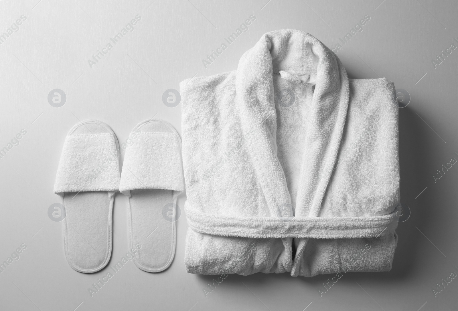 Photo of Clean folded bathrobe and slippers on white background, flat lay