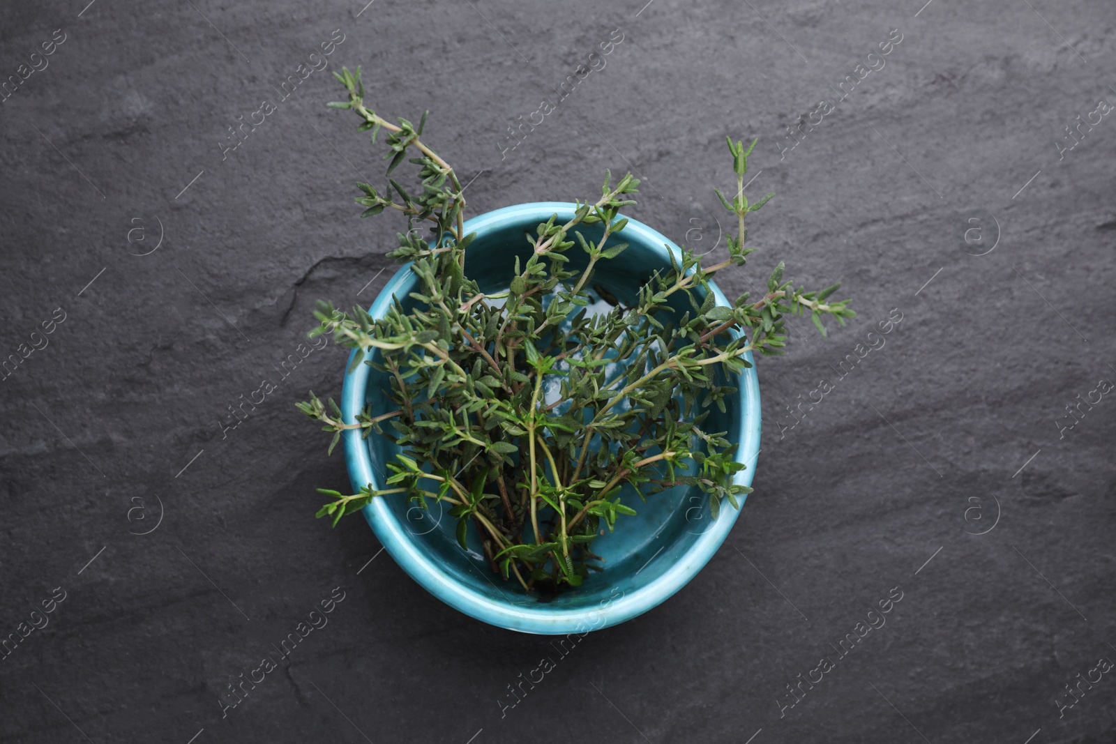 Photo of Bowl with fresh thyme on black table, top view