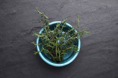 Photo of Bowl with fresh thyme on black table, top view