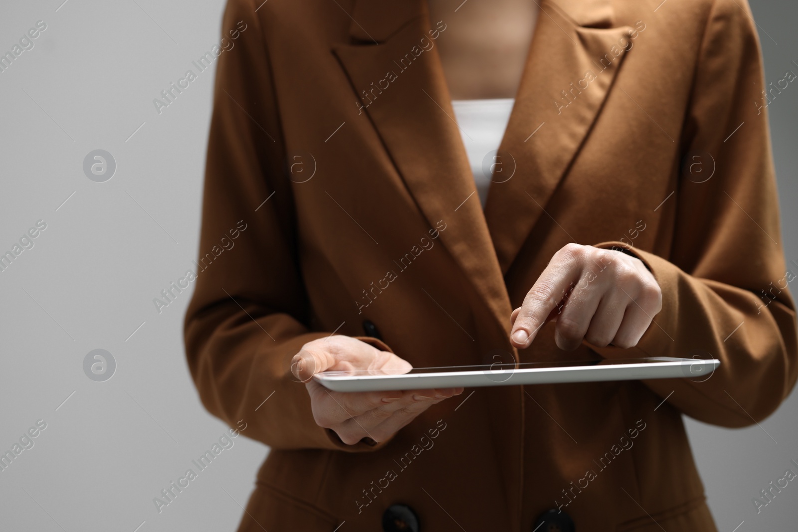 Photo of Closeup view of woman using modern tablet on grey background