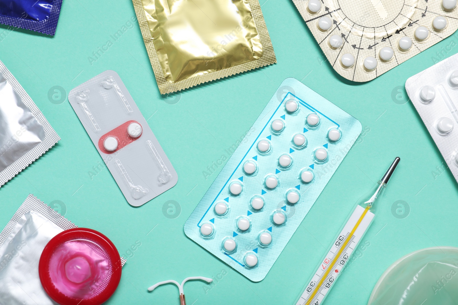 Photo of Contraceptive pills, condoms, intrauterine device and thermometer on turquoise background, flat lay. Different birth control methods