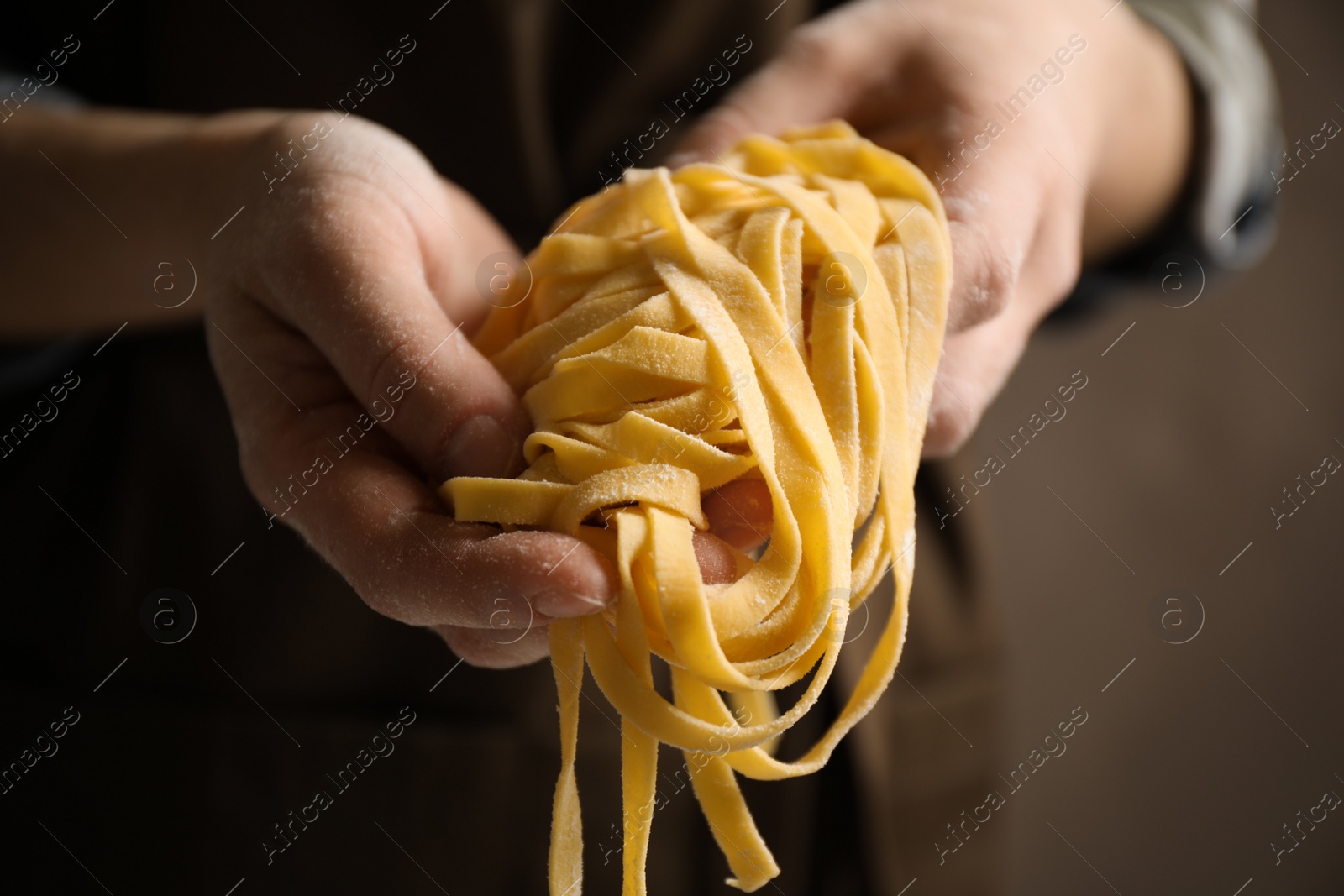 Photo of Woman holding pasta on brown background, closeup