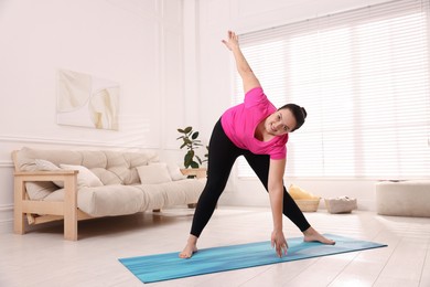 Overweight woman doing exercise at home, space for text