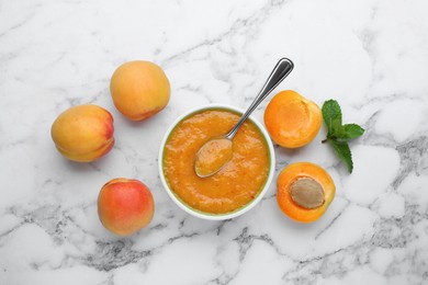 Apricot puree in bowl and fresh fruits with mint on white marble table, flat lay
