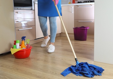 Woman washing floor with mop in kitchen. Cleaning service