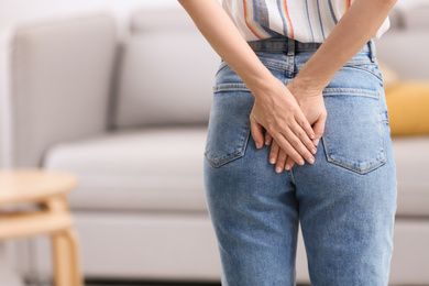 Young woman suffering from hemorrhoid at home, closeup. Space for text