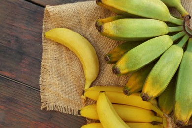 Photo of Different sorts of bananas on wooden table, flat lay