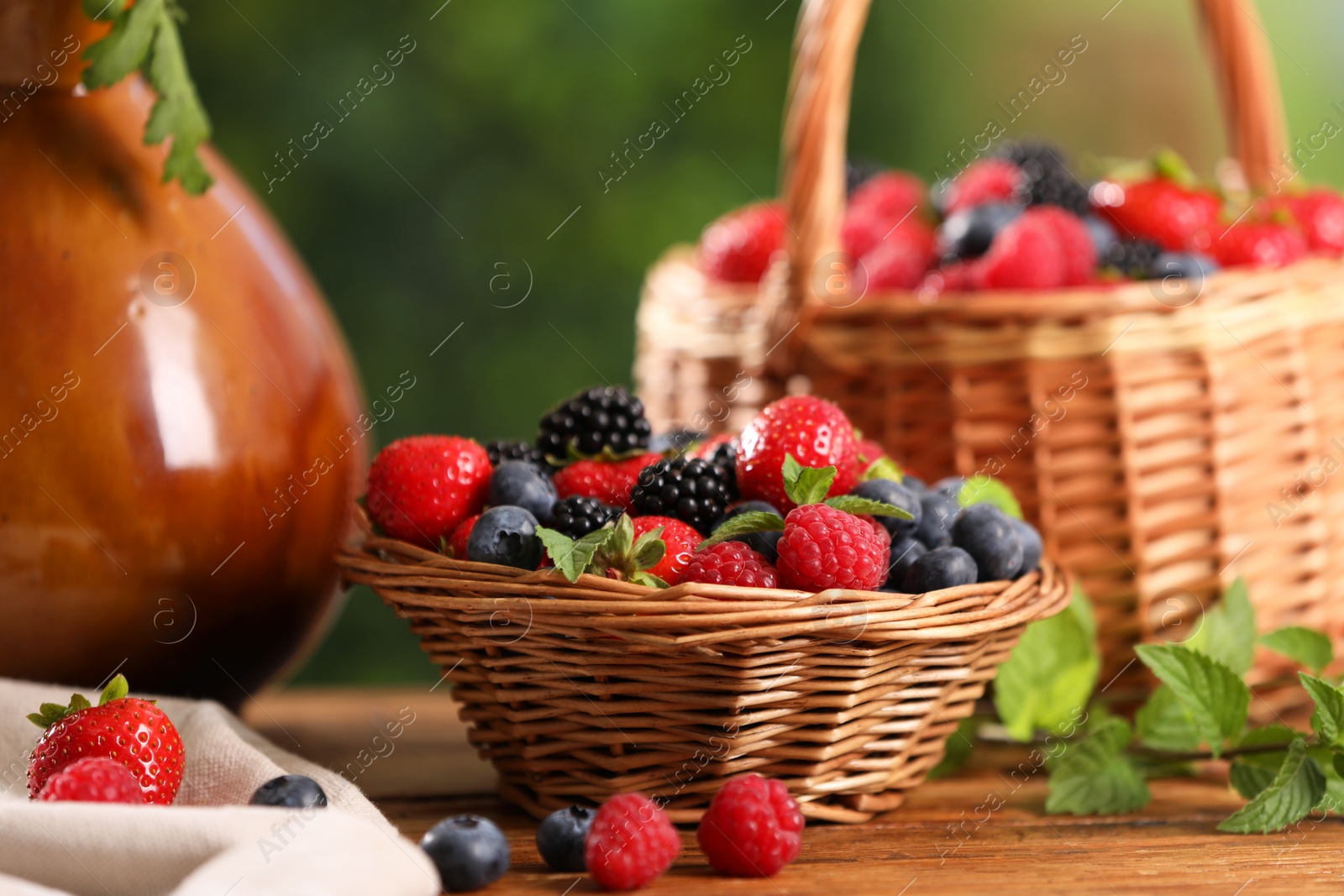 Photo of Different fresh ripe berries and mint on wooden table outdoors