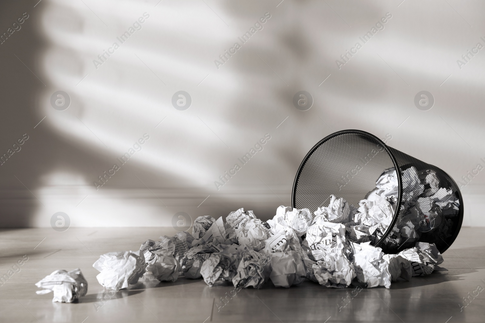 Photo of Metal bin with crumpled paper near white wall indoors, space for text. Rubbish recycling