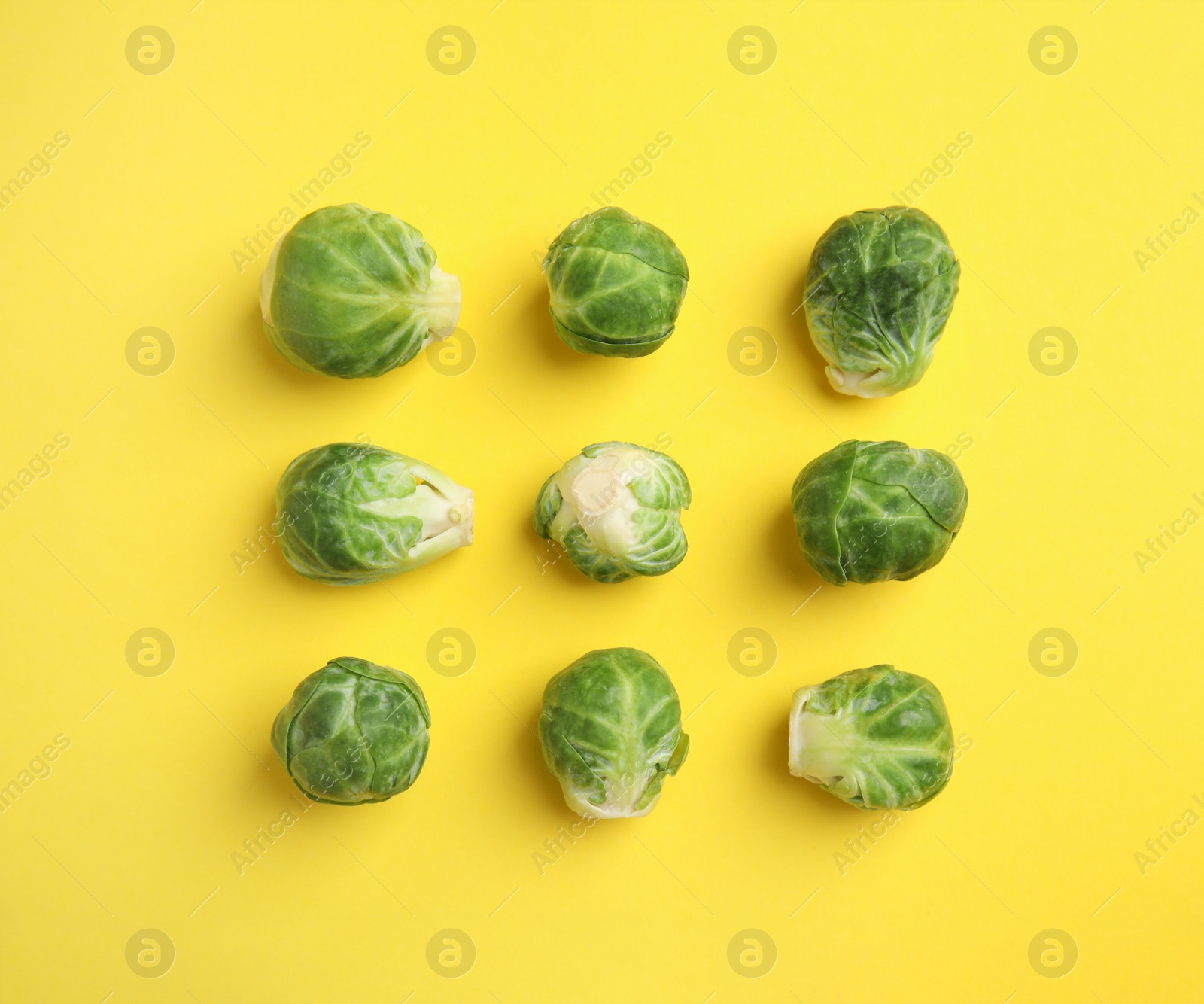 Photo of Fresh Brussels sprouts on yellow background, flat lay