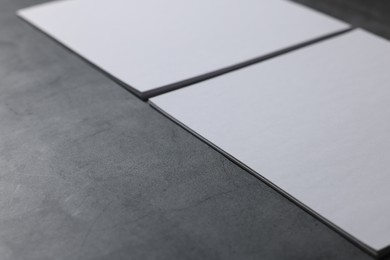 Photo of Blank paper sheets on grey textured table, closeup. Mockup for design