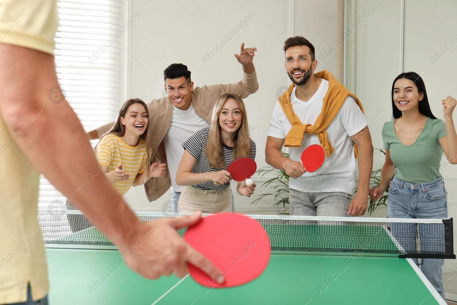 Photo of Happy friends playing ping pong together indoors