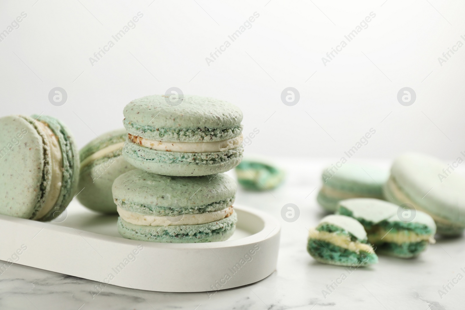 Photo of Delicious macarons on white marble table, space for text. Sweet dessert