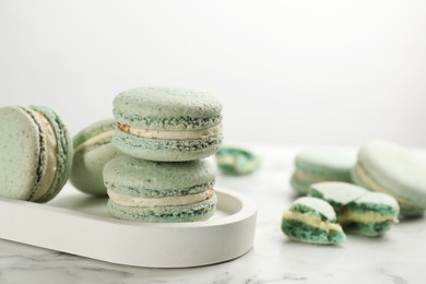 Delicious macarons on white marble table, space for text. Sweet dessert