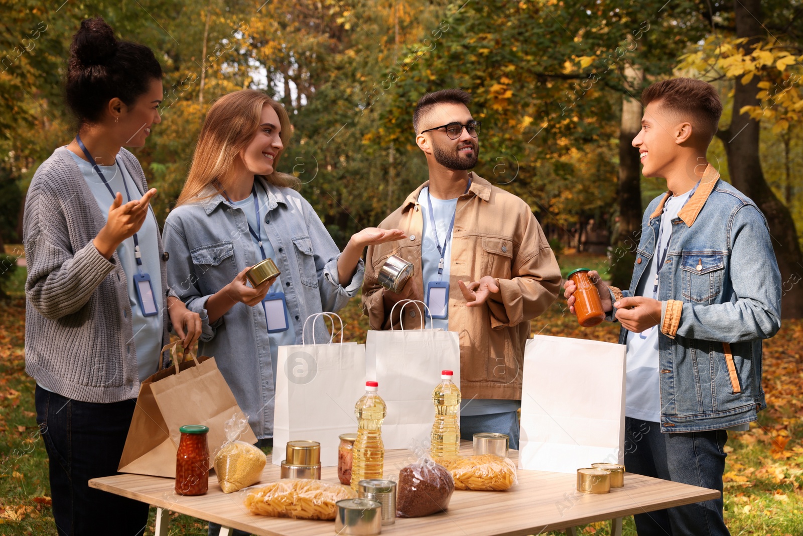 Photo of Group of volunteers packing food products at table in park