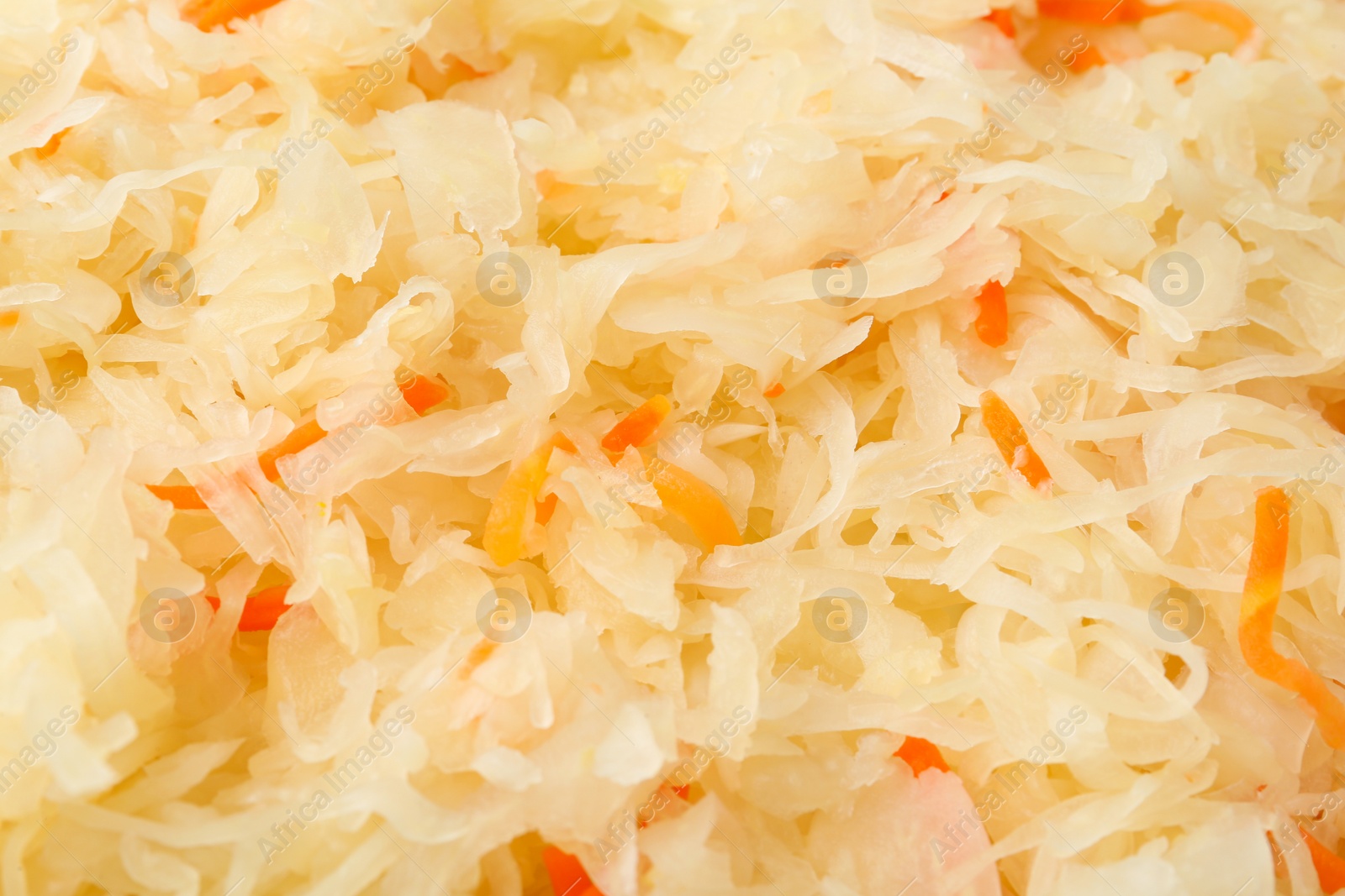 Photo of Tasty fermented cabbage with carrot as background, closeup