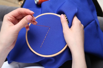 Photo of Woman with sewing needle and thread embroidering on cloth, closeup