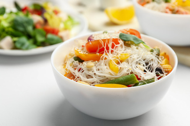 Tasty cooked rice noodles with vegetables on white table