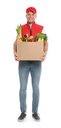 Delivery man with box of fresh vegetables on white background