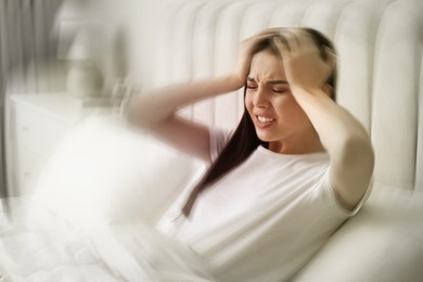 Image of Young woman suffering from migraine in bed at home