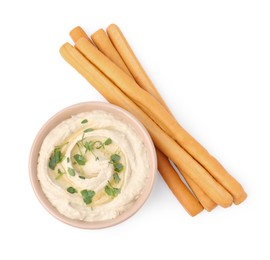 Delicious grissini sticks and hummus isolated on white, top view