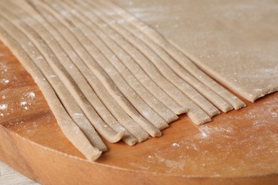 Photo of Making homemade soba (buckwheat noodles) on wooden board, closeup