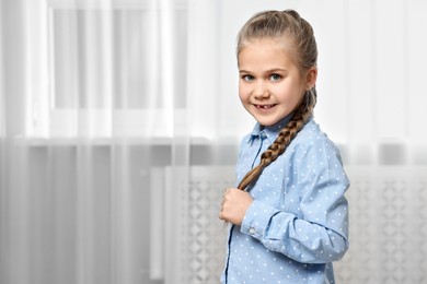 Cute little girl with braided hair indoors. Space for text