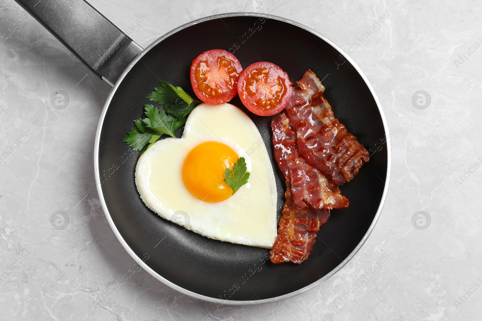 Photo of Tasty breakfast with heart shaped fried egg on grey table, top view