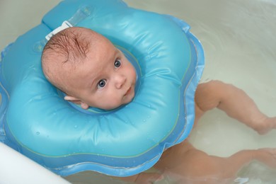 Cute little baby swimming with inflatable ring in bath