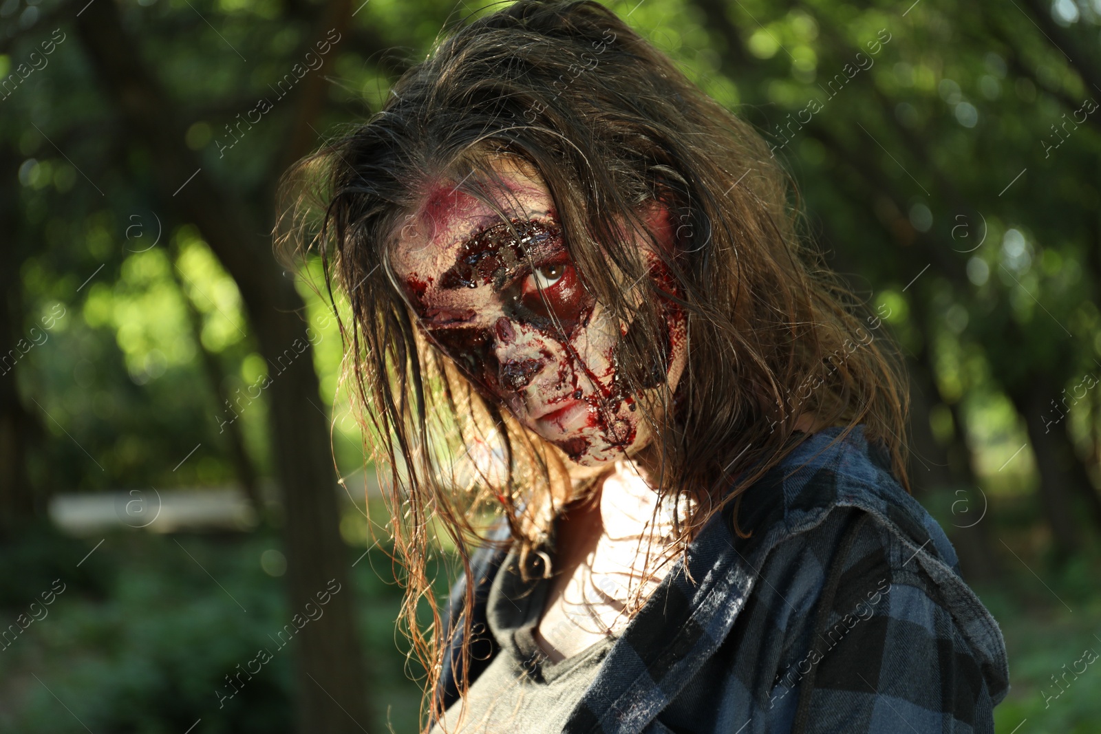 Photo of Scary zombie with bloody face outdoors. Halloween monster