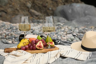 Photo of White wine and fresh fruits on picnic blanket outdoors
