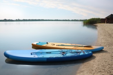 SUP boards with paddles on river shore