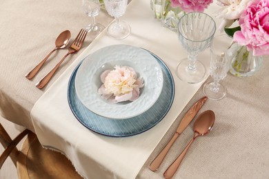 Stylish table setting with beautiful peonies and golden cutlery indoors