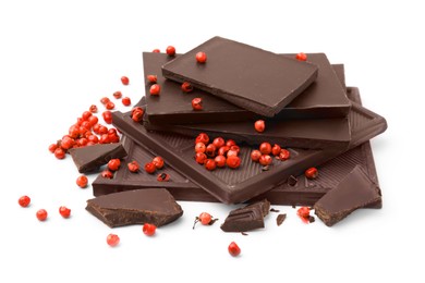 Photo of Red peppercorns and pieces of dark chocolate isolated on white