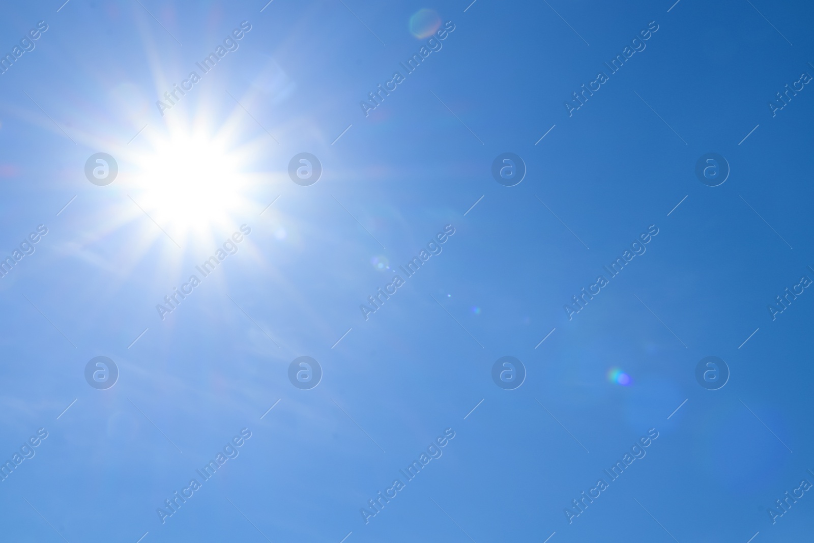 Photo of Bright sun in blue sky. Halo effect