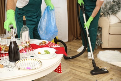 Photo of Cleaning service team working in messy room after New Year party, closeup