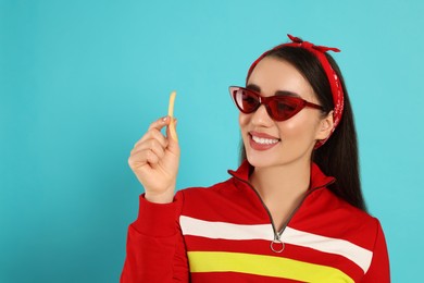 Beautiful young woman with French fries on light blue background. Space for text