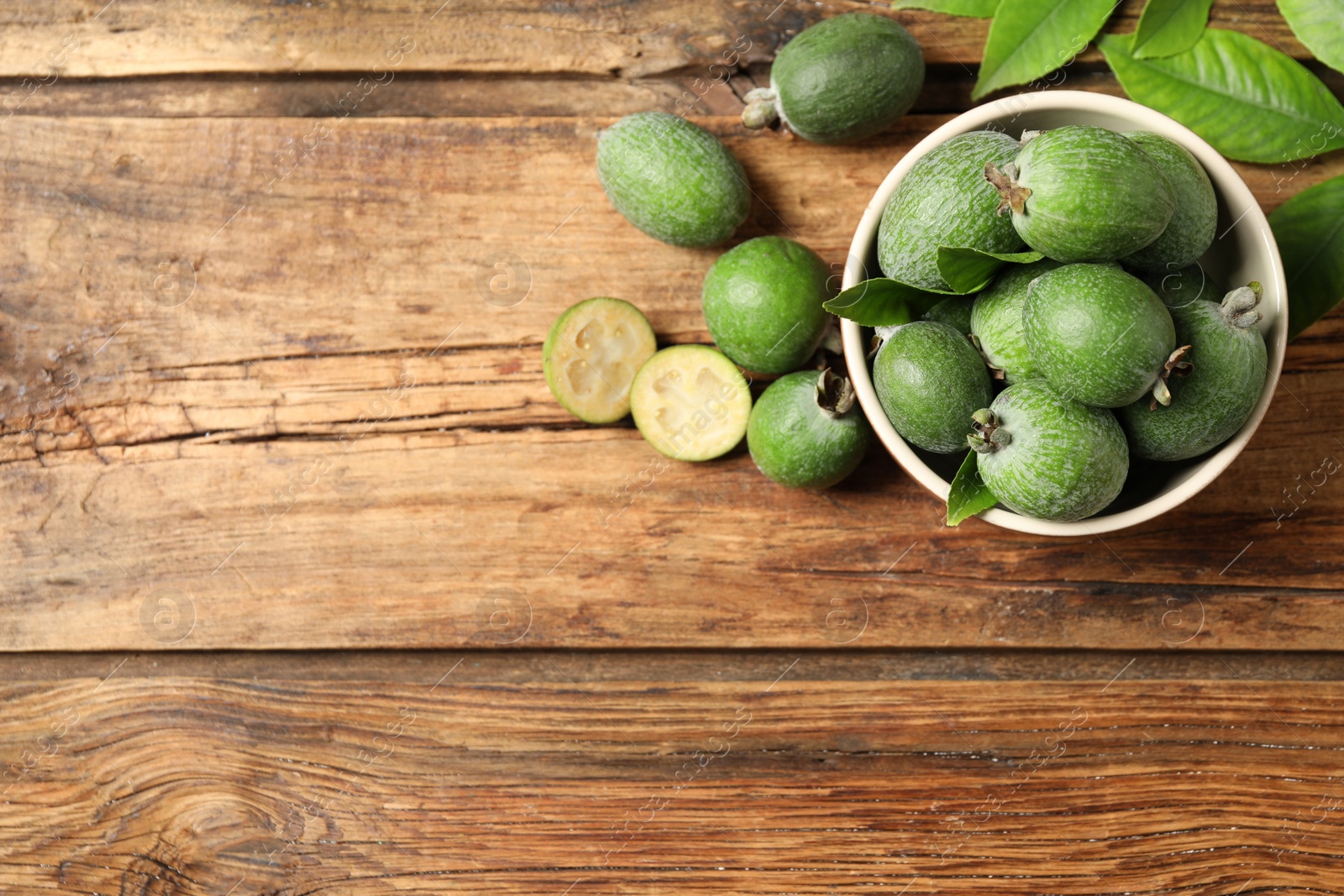 Photo of Flat lay composition with fresh green feijoa fruits on wooden table, space for text