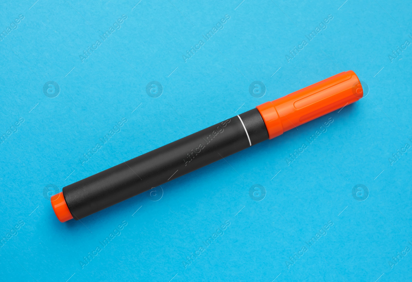 Photo of Bright orange marker on light blue background, top view