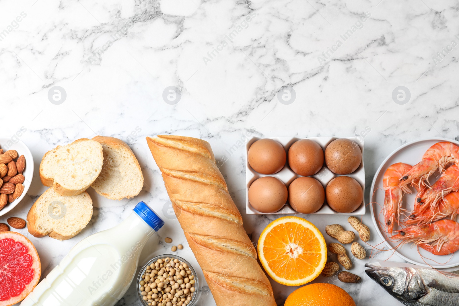 Photo of Flat lay composition of different products and space for text on white marble table. Food allergy concept