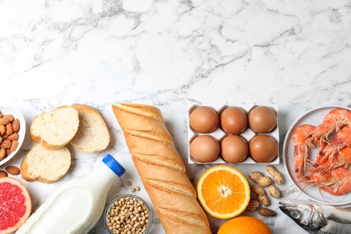 Photo of Flat lay composition of different products and space for text on white marble table. Food allergy concept