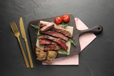 Photo of Delicious grilled beef with vegetables and rosemary served on dark gray table, flat lay