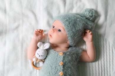 Cute newborn baby with teething toy on white blanket, top view