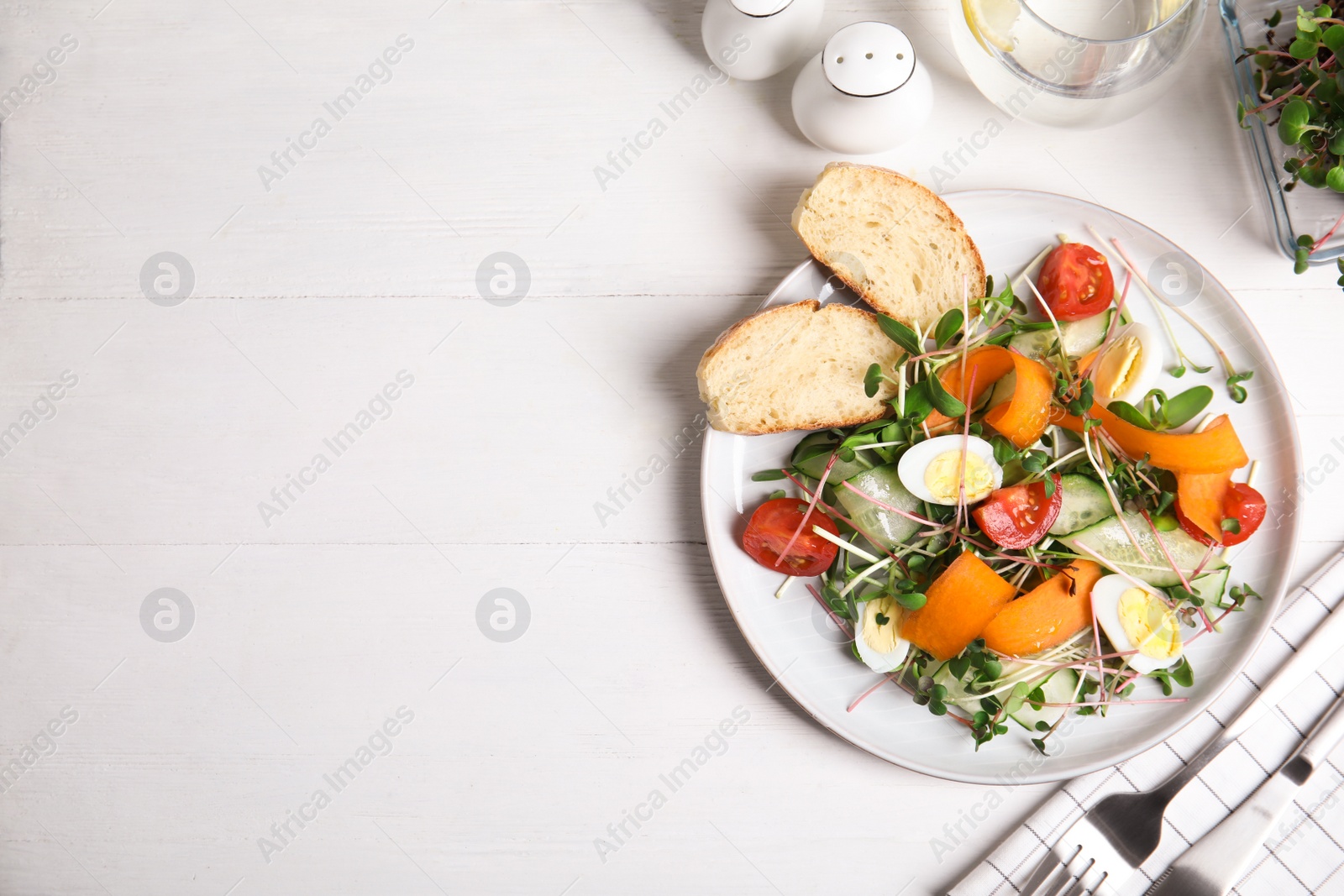 Photo of Salad with fresh organic microgreen in plate on white table, flat lay. Space for text