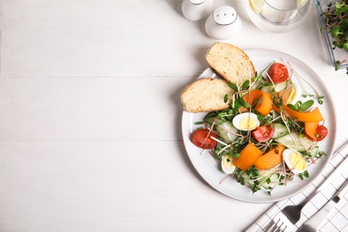 Salad with fresh organic microgreen in plate on white table, flat lay. Space for text