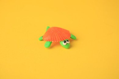 Photo of Turtle made from plasticine on yellow background. Children's handmade ideas