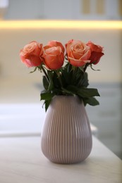 Photo of Vase with beautiful roses on countertop in kitchen. Interior design